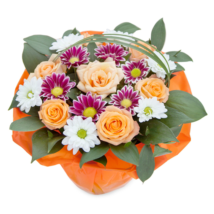 An elevated curated bouquet poised against a spotless white background blends the natural vibrancy of Sipson's flora with classic design. The focal point is a lush gathering of roses, celebrating a gradient from gentle peach to rich orange, each flower's petals meticulously layered and partway unfurled, evoking both softness and exuberance. These roses are flanked by an assortment of chrysanthemums-some radiate like miniature stars with white petals and bright green centers, while others present an intense magenta-purple, their centres glowing with lively lime hues. The generous use of dark green foliage, possibly ruscus or another broad-leaved plant, imparts a grounding, forest-like base that highlights each bloom's unique character. A single, sweeping strand of glossy bear grass loops over the bouquet, its shape adding both height and fluidity, reminiscent of the winds that flow through Harmondsworth Moor. At the base, a wrap of vivid orange tissue creates a crisp flare of colour and frames the composition beautifully, reinforcing its status as a celebratory gift. Perfectly suited for commemorating moments great and small-be it a birthday in Sipson or a heartfelt thank you-this bouquet brims with texture, color, and the skilled hand of a local florist, projecting both sophistication and a warmly personal charm.