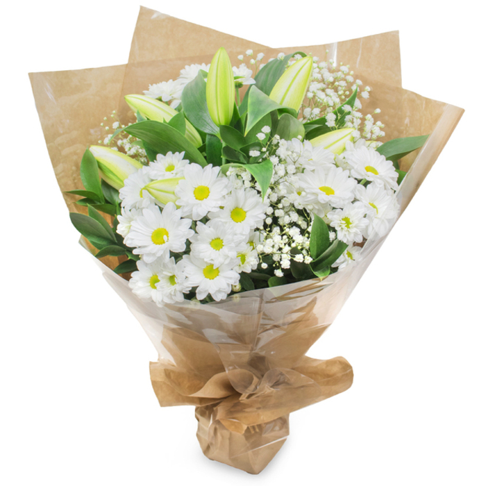 An elegant, upright hand-tied bouquet captured against a white background, where shades of white and fresh green come together in a composed, approachable arrangement. The principal flowers are white chrysanthemums that resemble small daisies: multiple slender petals fan from a cheerful yellow centre, creating a crisp, friendly focal mass. Rising above and threaded among those are pale green-yellow lily buds, some with faint stripes; their closed forms bring sophisticated anticipation, a feeling that the bouquet will open and change over the next days. Tiny sprays of white baby's breath (Gypsophila) float through the composition like soft mist, adding airiness and gentle texture that complements the more substantial chrysanthemum heads. Dark green leaves and sturdy stems provide depth and a natural backdrop that makes the whites appear luminous. Wrapped with a layer of natural brown kraft paper that is gently crinkled for an organic, market-style look, the bouquet is finished with a clear, glossy cellophane outer layer that keeps petals safe while reflecting a little light; the base is gathered and tied so the bouquet can stand or be carried with ease. Under soft, neutral lighting you can almost detect a faint, clean fragrance - a hint of meadow grass and fresh cut greens - and the tactile contrast between the crinkled paper and the smooth cellophane. For locals who know the Bath Road, Harmondsworth Lane or the village green, this is the kind of thoughtful, versatile arrangement you'd send for a birthday, to say thank you, for new beginnings, or to offer calm sympathy.