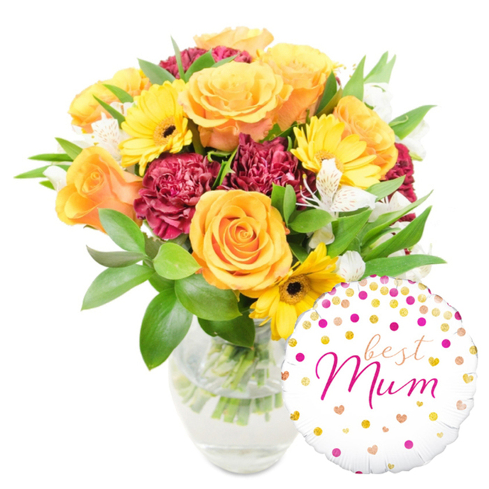 An uplifting, meticulously balanced floral arrangement rests in a simple clear glass vase on a white field, the kind of present that announces celebration with quiet grace. Prominent in the centre-left are several large orange-leaning roses, their petals soft and spiralled, radiating a warm, peachy glow. Bright yellow gerbera daisies peek through like cheerful beacons, their flat, radiant faces creating friendly contrast against the roses. Deep burgundy carnations add weight and textural richness; their ruffled layers give the bouquet a plush, tactile depth that invites touch. Interspersed among these are delicate white alstroemeria, their narrow, speckled petals offering a refined, almost porcelain-like accent that lifts the stronger colours. Lush green foliage-broad glossy leaves and fine sprigs-surrounds and supports the blooms, forming a verdant backdrop that enhances every hue. The glass vase reveals clean water and visible stems, an honest, crafted detail that speaks to careful vase work and freshness. To the lower right, slightly overlapping the vase, sits a white round Mylar balloon decorated with scattered gold and hot-pink polka dots and tiny heart motifs; the centre is emblazoned with best Mum in an elegant fuchsia script, the word Mum prominent and lovingly styled. The overall impression is of a beautifully composed gift, perfect for Mother's Day or a special birthday, something many families in Sipson village or on nearby Bath Road would choose to send to make a mother feel seen and celebrated.